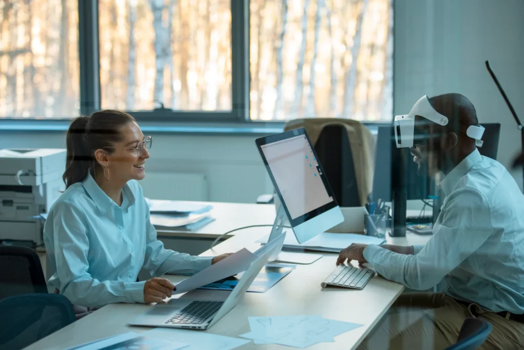 Two professionals discussing work while using AI-powered technology in a modern office environment.